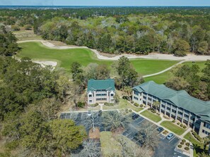 An aerial view of a golf course with a clubhouse and parking lot.