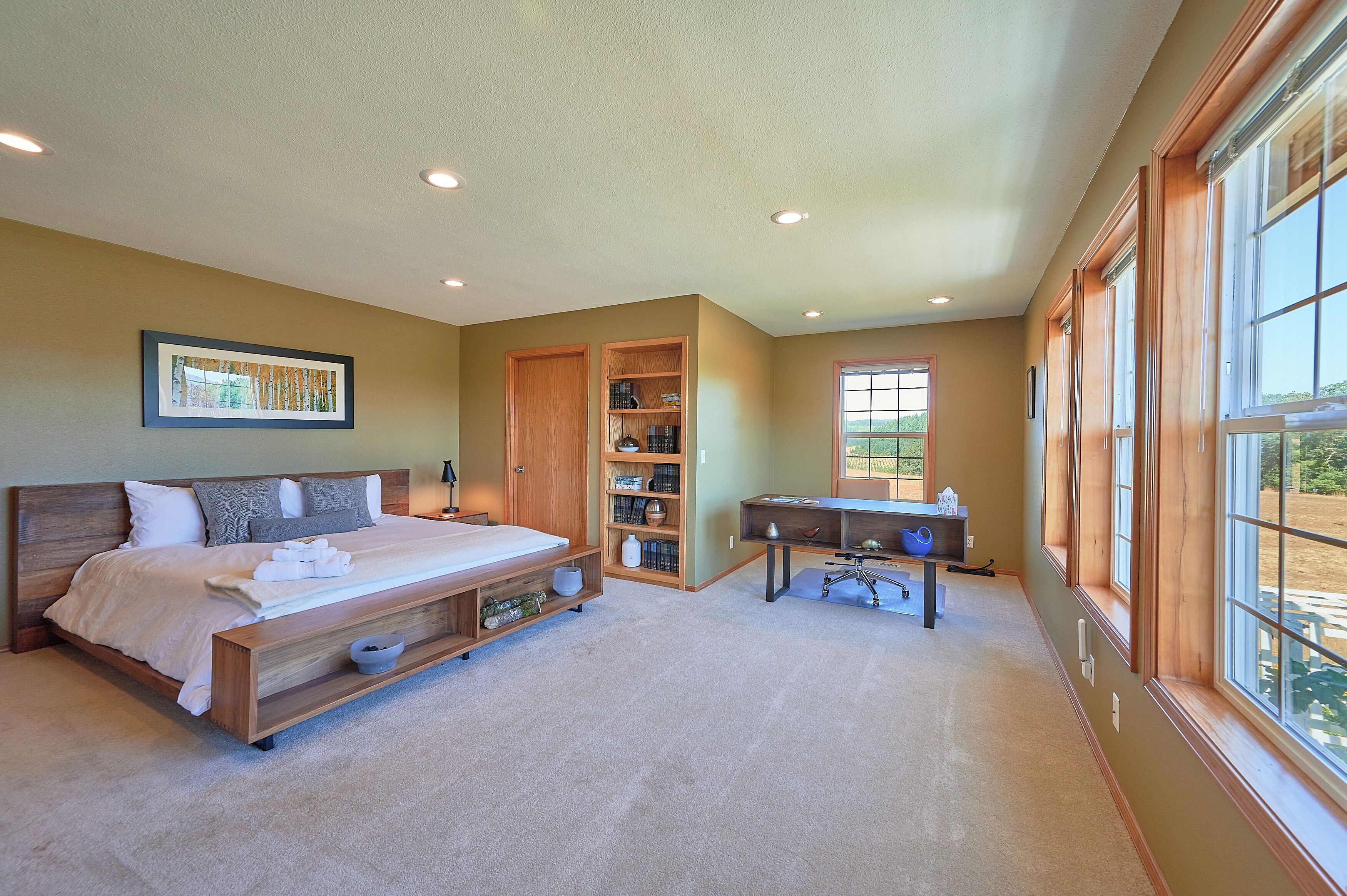 A bedroom with a large bed, a desk, and a bookshelf.