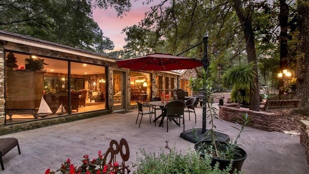 An outdoor patio area with stone flooring, outdoor seating, and potted plants. - 8 acres of fun & relaxation in a beautiful Rock Cottage with a pool and hot tub (Tomball)