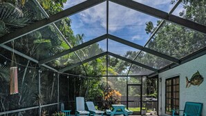 A covered swimming pool with lounge chairs and potted plants.