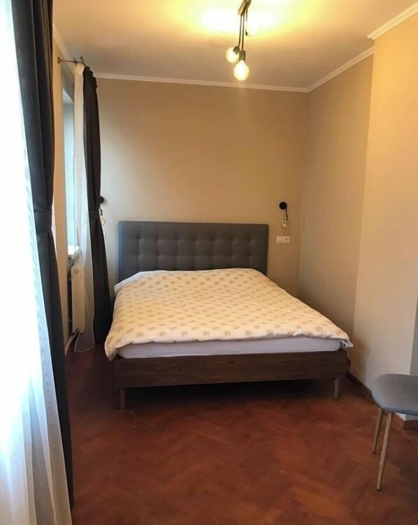 Cozy retreat with a single bed, tufted headboard, and patterned bedspread, set against a wooden floor.