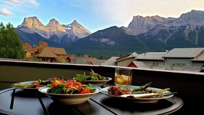 Ein Tisch mit Speisen und einem Getränk, mit Blick auf eine Berglandschaft.