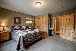 A bedroom with a large bed, wooden wardrobe, a nightstand, and a lamp. - Lakeside Mountain Retreat with HOT TUB! (Grand Lake)
