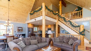 A spacious living area with a wooden staircase, a dining area, and a kitchen. - Lakeside Mountain Retreat with HOT TUB! (Grand Lake)