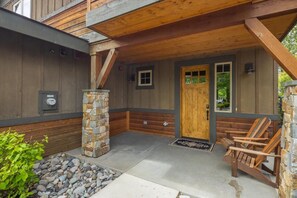 Una cabaña de madera con un pilar de piedra, una puerta de madera y un banco en el exterior.