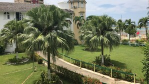 A residential area with a white building, a tower with a conical roof, and palm trees. - JAMAICA ON THE BEACH (Ocho Rios)