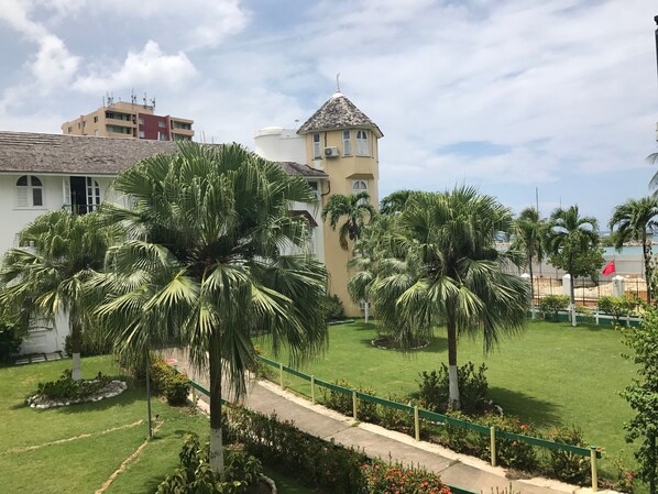 A residential area with a white building, a tower with a conical roof, and palm trees.
