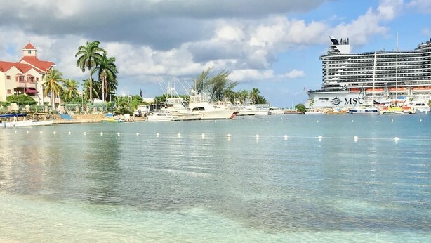 A beach with clear water, a cruise ship, and a building with a red roof. - JAMAICA ON THE BEACH (Ocho Rios)