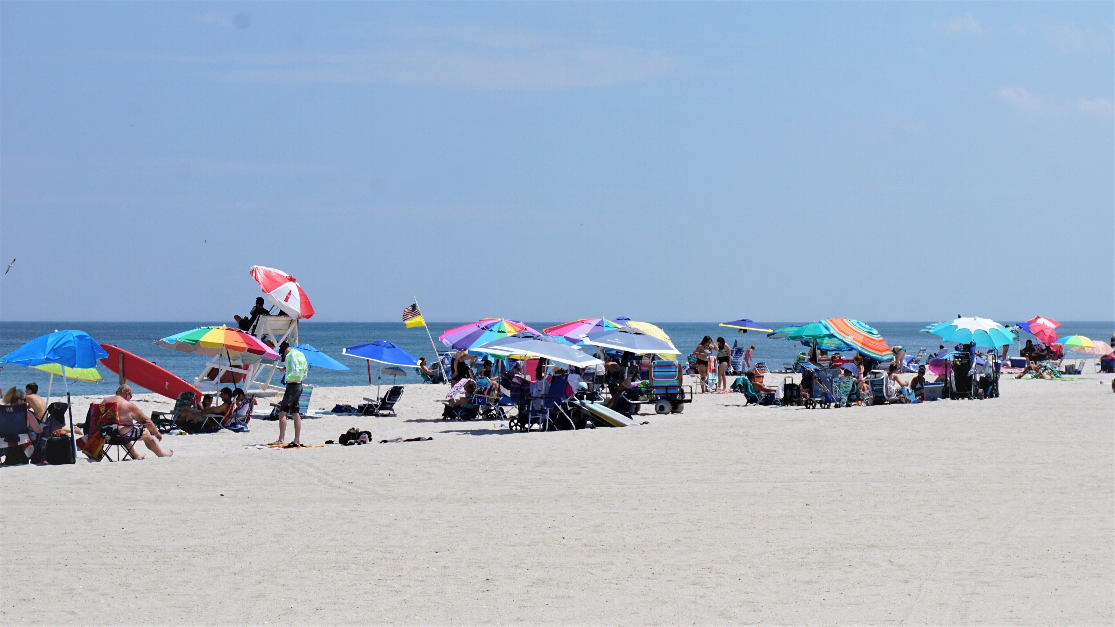 Una spiaggia con numerosi ombrelloni e lettini colorati.