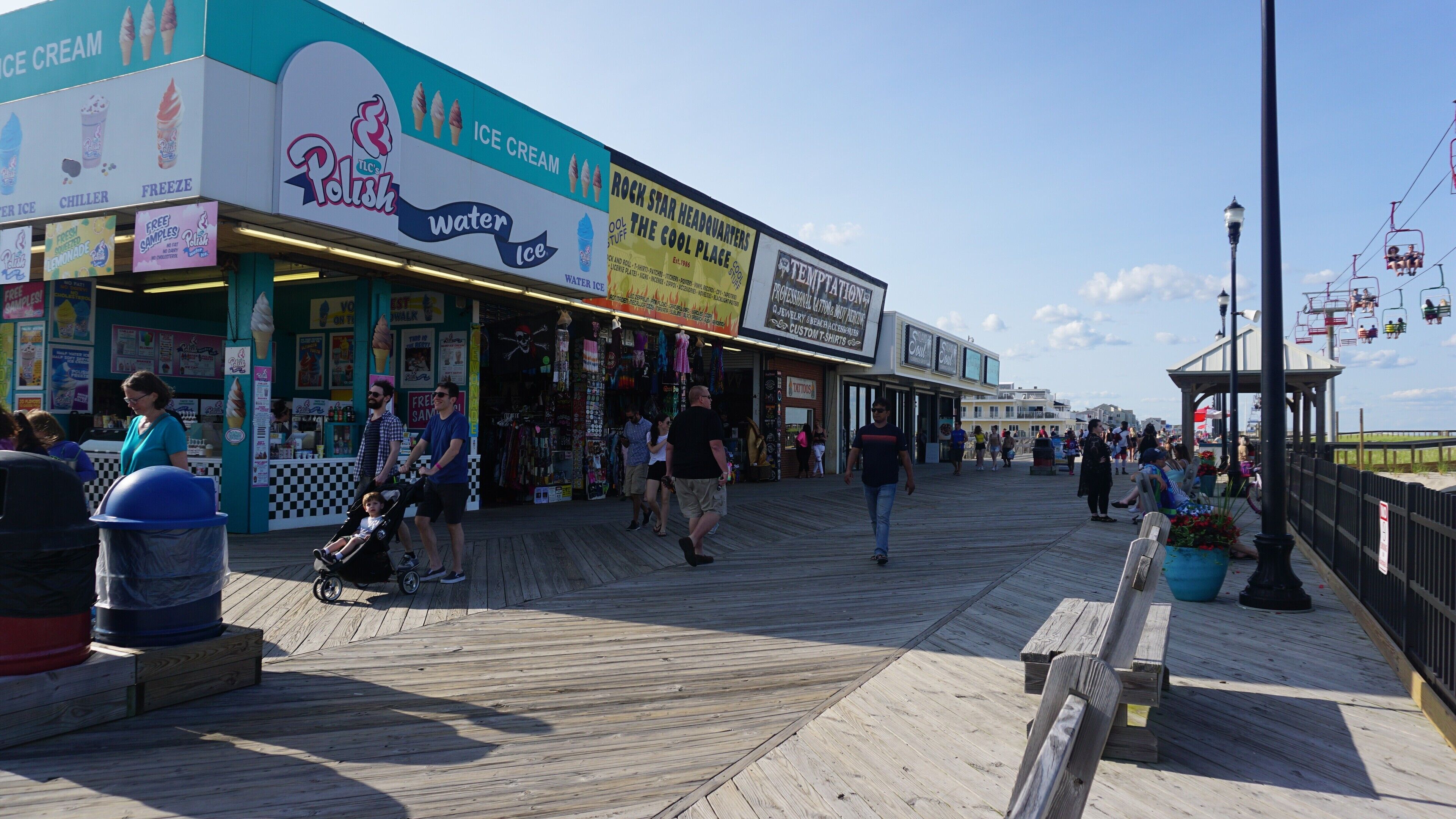 A boardwalk with shops, including a water ice stand and a tattoo parlor.