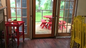 Una habitación con piso de madera, una mesa roja y una silla amarilla.