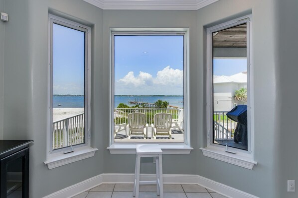 A room with a view of a beach and pier, featuring a white chair and a small table. - ocean sounds retreat (Navarre)