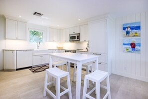 A modern kitchen with white cabinetry, a central island, and a painting on the wall.