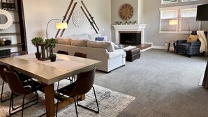 A spacious living room with a fireplace, a dining area with a table and chairs, and a cozy seating area with a sofa and ottoman.