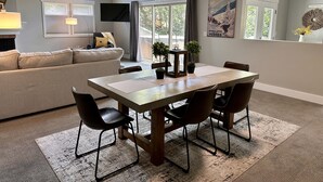 A modern living room with a dining area, large windows, and a flat-screen TV.