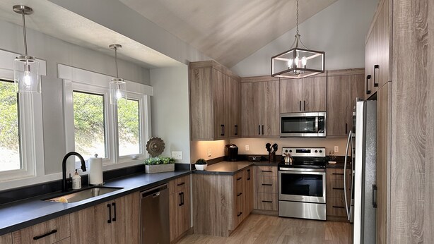 A modern kitchen with wooden cabinets, stainless steel appliances, and pendant lighting.