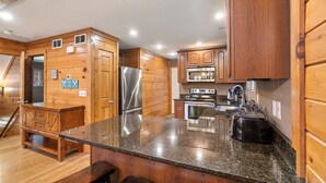 A kitchen with wooden cabinets, a granite countertop, stainless steel appliances, and a bench. - Bottoms Up double deck dock w/ slide, hot tub, near famous 'jumping bridge' (LaFollette)