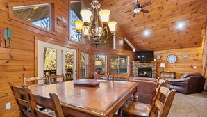 A wooden interior with a dining table, chairs, a fireplace, a television, and a ceiling fan. - Bottoms Up double deck dock w/ slide, hot tub, near famous 'jumping bridge' (LaFollette)