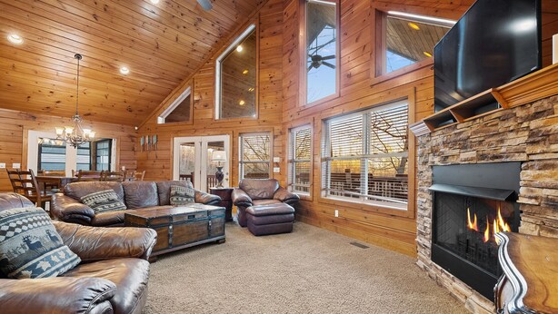 A spacious living room with a fireplace, leather sofas, and a large TV. - Bottoms Up double deck dock w/ slide, hot tub, near famous 'jumping bridge' (LaFollette)