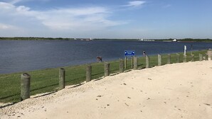 A sandy beach with a wooden fence and a sign indicating no parking on the grass. - Cozy Cottage near the lake (Big Lake, LA) (Lake Charles)
