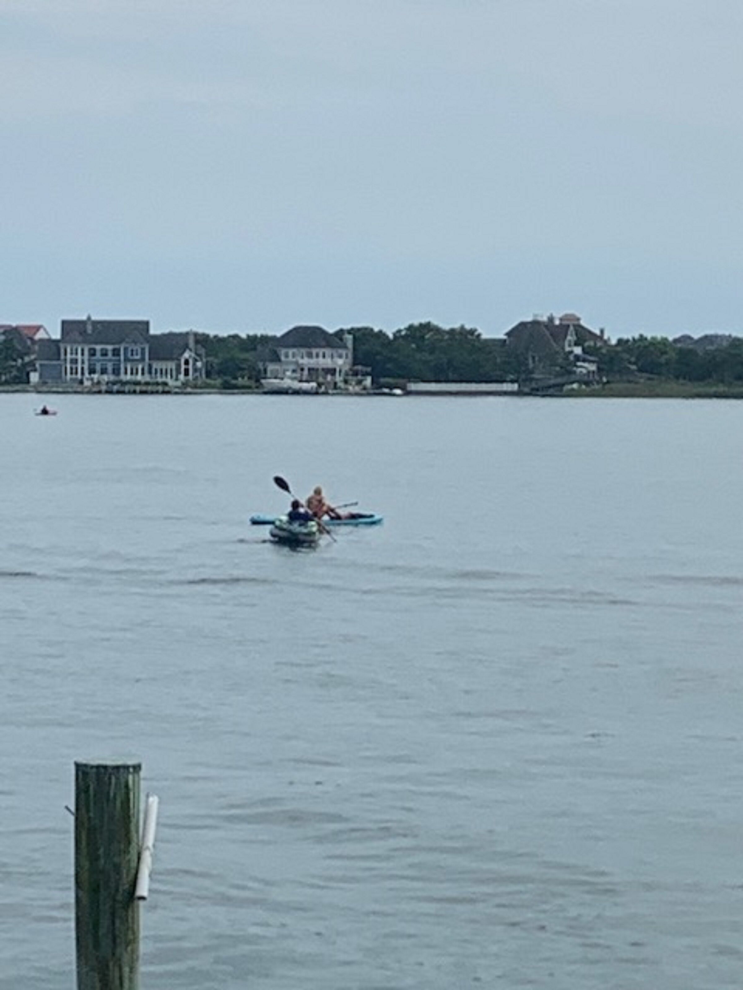 A calm body of water with a kayak in the foreground and houses in the background.