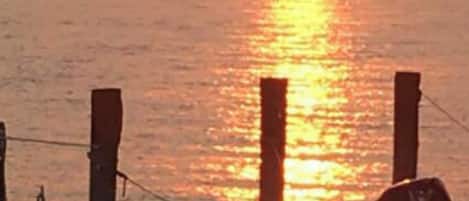 A sunset over a body of water with a wooden dock and a boat.