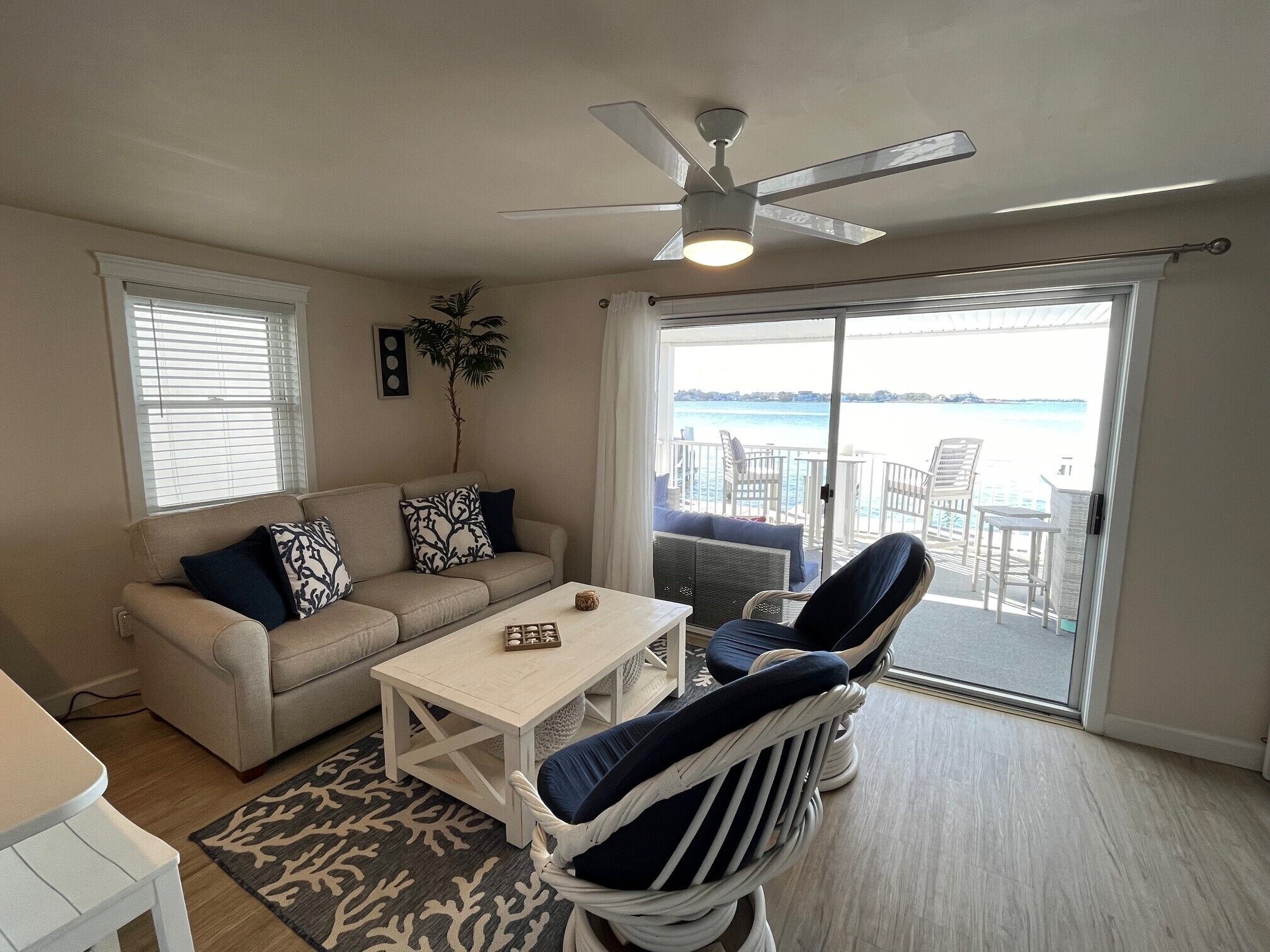 Un salon comprenant un canapé, des fauteuils, une table basse et une vue sur la mer, accessible par une porte coulissante.