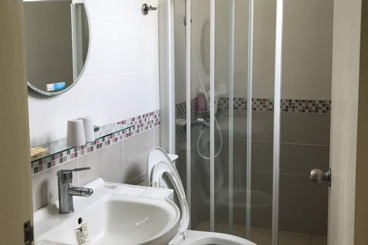 A bathroom with a toilet, sink, and glass shower enclosure.