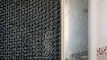 A bathroom with a toilet, a shower enclosure, and a tiled wall.