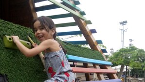 Un enfant qui grimpe sur une structure d’escalade en bois, dotée de barres horizontales de couleurs vives.