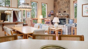 Un salon spacieux doté d’une cheminée, de sièges confortables et de grandes fenêtres offrant une vue sur l’extérieur.