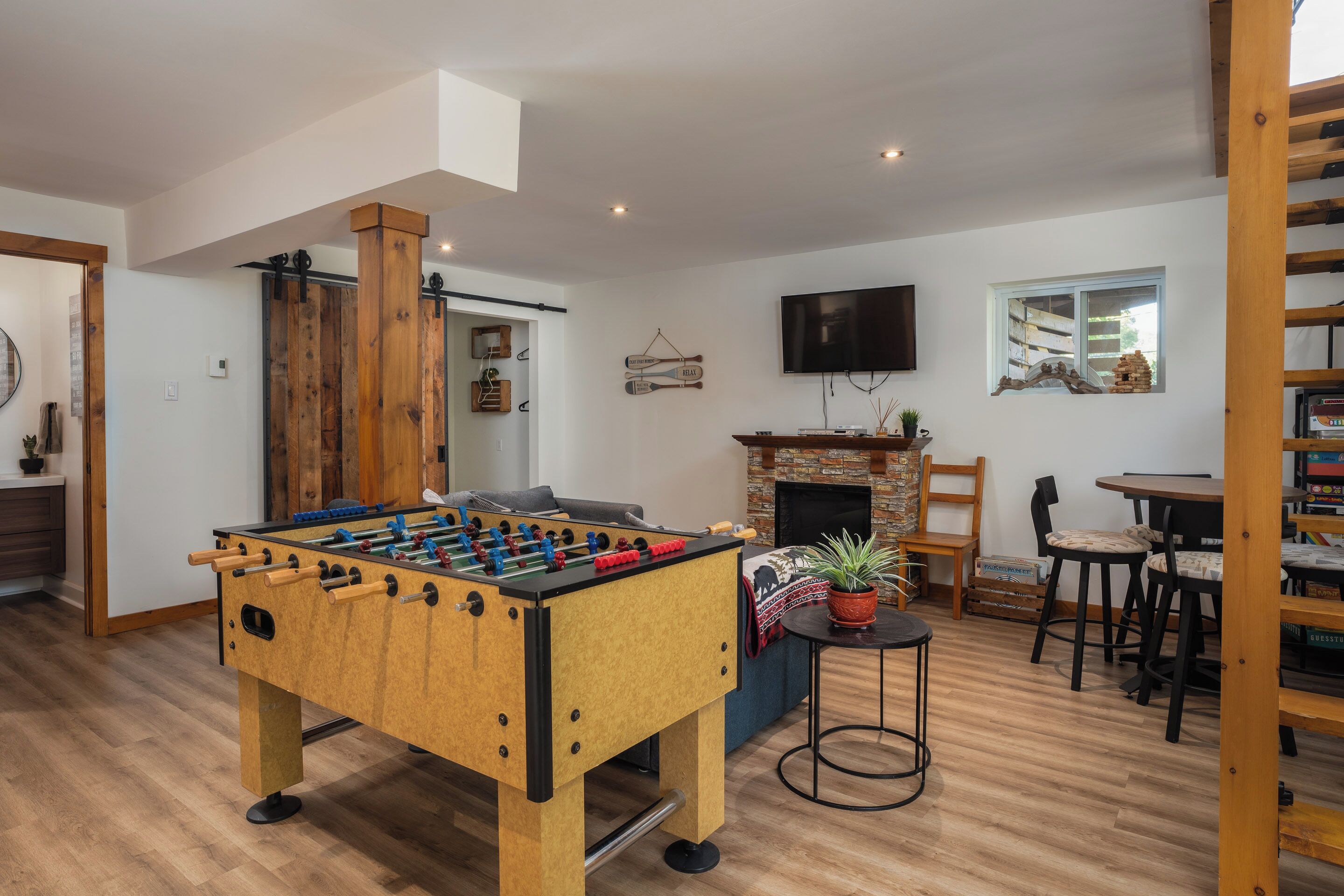 A cozy living room with a foosball table, a fireplace, and a TV mounted on the wall.
