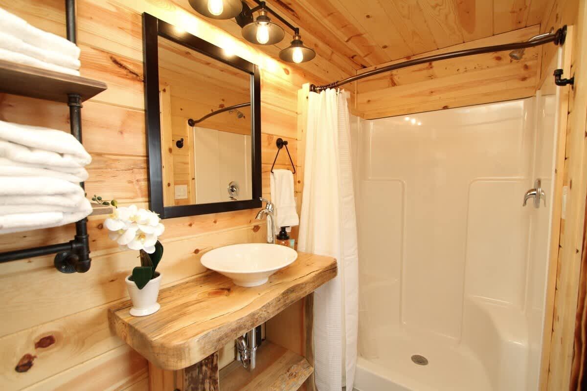 A wooden bathroom with a wooden sink, a mirror, and a shower.