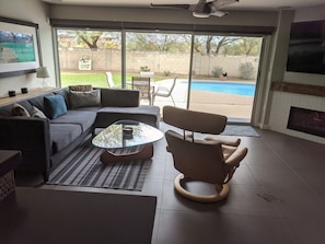 A modern living room with a glass coffee table, a sofa, and a recliner.