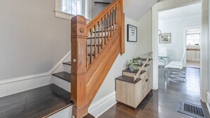 A wooden staircase with a handrail, a small plant on a wooden stand, and a white chair in a hallway. -  A luxury and modern estate. Free airport transfer with Tesla Model X! (Peoria)