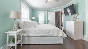 A bedroom with a bed, nightstands, a dresser, a ceiling fan, and a TV mounted on the wall. -  A luxury and modern estate. Free airport transfer with Tesla Model X! (Peoria)
