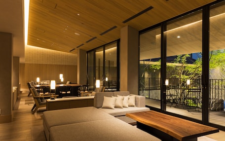A modern living room with a sofa, a wooden coffee table, and a dining area with chairs and a table.