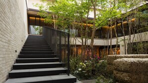 A modern building with a staircase leading to an upper level, surrounded by greenery and stone features. - Hotel Metropolitan Kamakura (Kamakura)