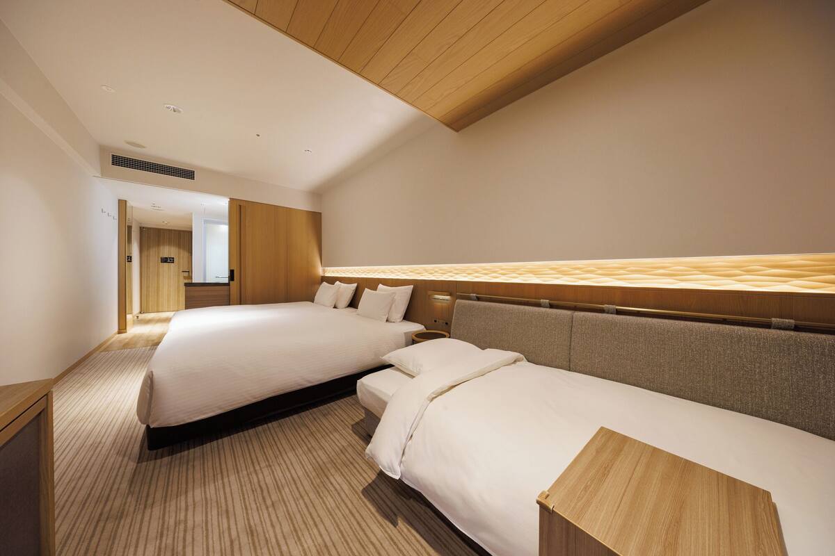 Quarto de hotel com duas camas, teto de madeira e vista para o corredor.