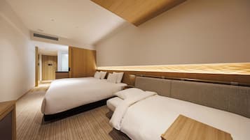 Een hotelkamer met twee bedden, een houten plafond en uitzicht op de gang.