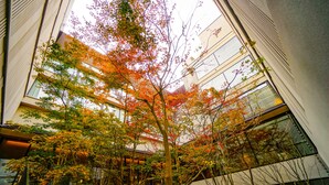 A multi-story building with a central atrium featuring trees with autumn foliage. - Hotel Metropolitan Kamakura (Kamakura)