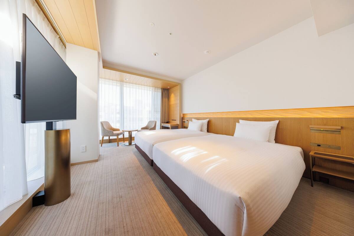 Quarto de hotel com uma cama grande, televisão, escrivaninha e uma cadeira.