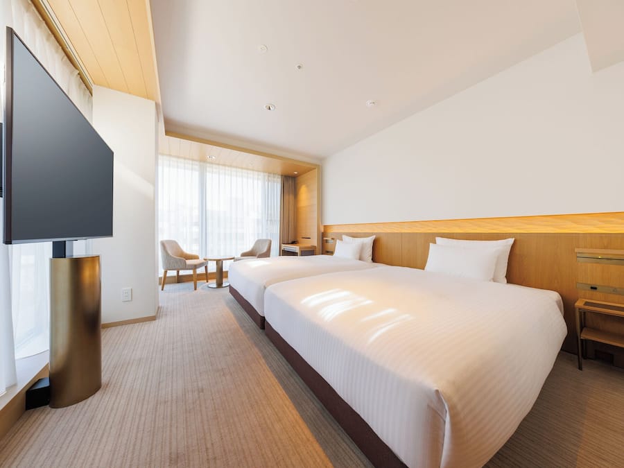 Ein Hotelzimmer mit einem großen Bett, einem Fernseher, einem Schreibtisch und einem Sessel.