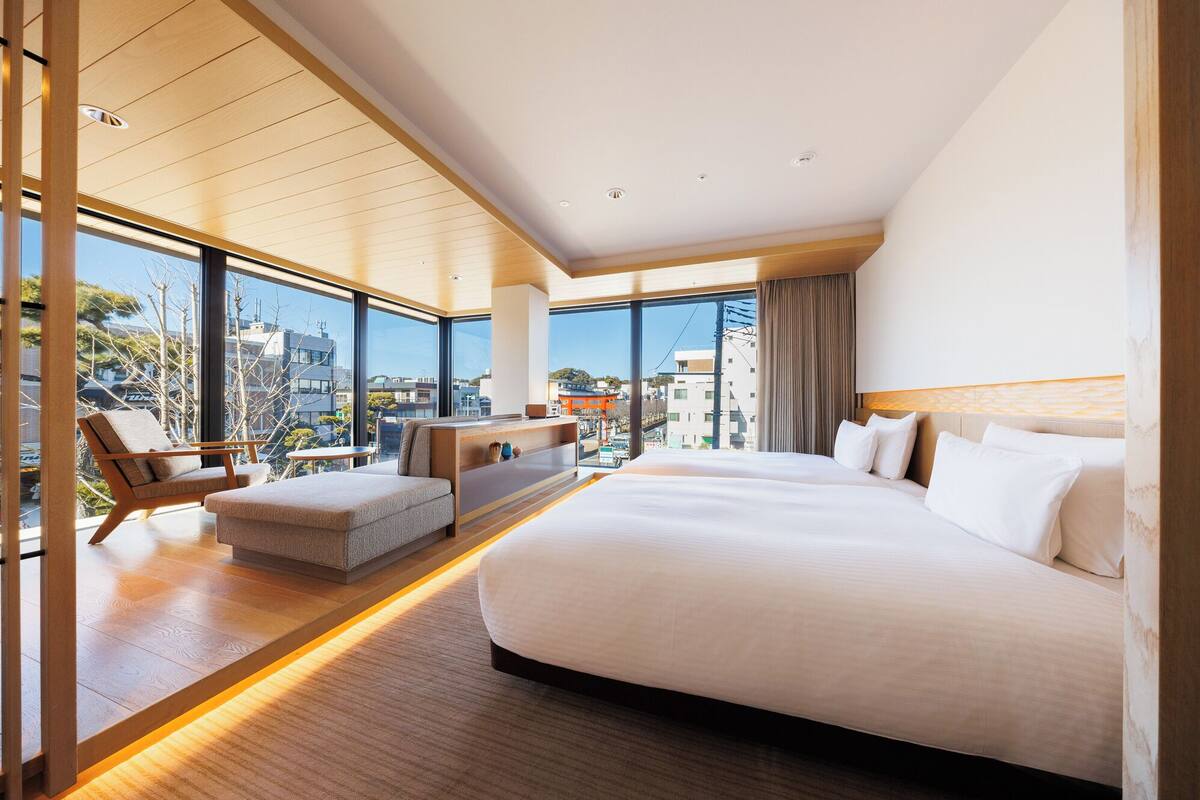 Quarto de hotel moderno com uma cama grande, área de estar com vista e varanda com vista panorâmica da cidade.