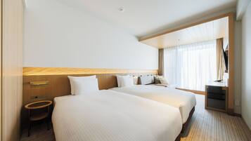 A hotel room with two beds, a desk, a chair, and a large window.