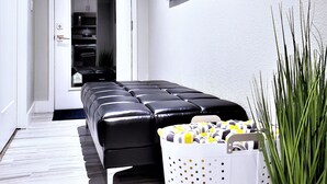 Een moderne woonkamer met een zwarte leren bank, een witte mand en een potplant.