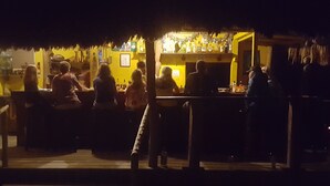 A bar area with a thatched roof, tables, and chairs.