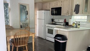 Une cuisine de taille réduite, dotée de meubles en bois, d’un réfrigérateur blanc, d’une cuisinière, d’un four à micro-ondes et d’un évier.