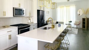 A modern kitchen with white cabinetry, a stainless steel refrigerator, and a central island with bar stools.