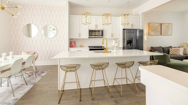 A modern kitchen with white cabinetry, a central island with bar stools, a microwave, and a refrigerator.